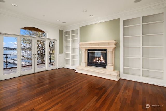 unfurnished living room featuring built in shelves, french doors, ornamental molding, and dark hardwood / wood-style flooring