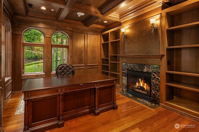 office with coffered ceiling, a high end fireplace, wood-type flooring, beam ceiling, and ornamental molding