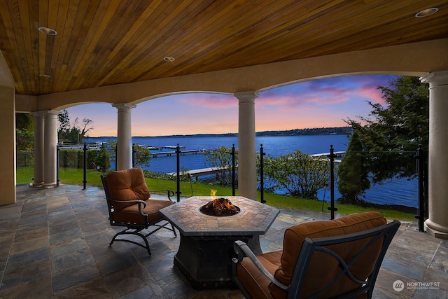 patio terrace at dusk with a fire pit and a water view