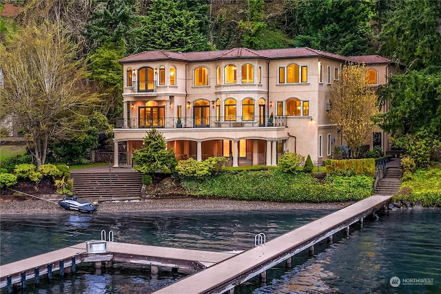 rear view of property featuring stairway, a water view, and stucco siding