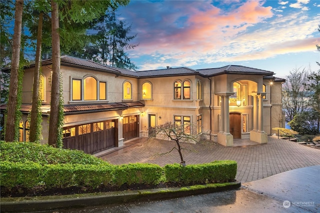 view of front facade featuring a tiled roof, driveway, and stucco siding