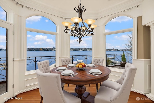 dining room featuring a chandelier, a water view, dark hardwood / wood-style floors, and ornamental molding