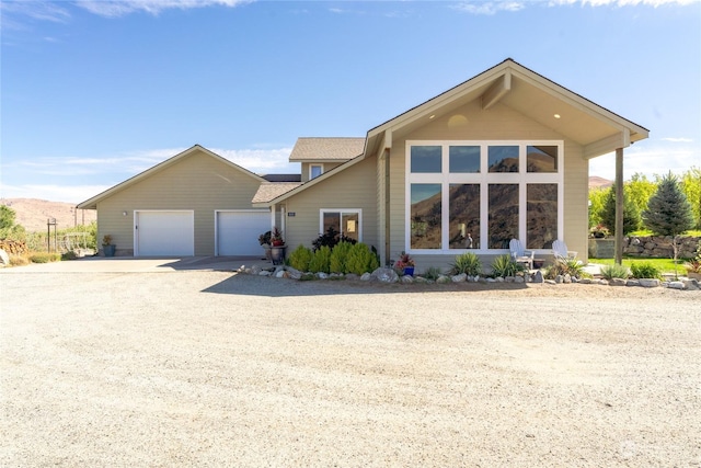 view of front facade featuring driveway, a garage, and a shingled roof