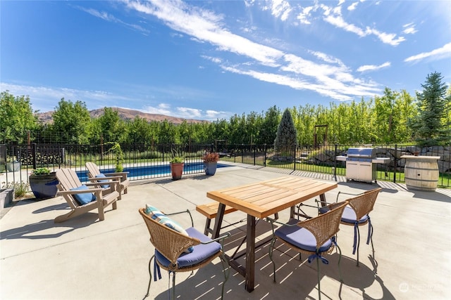 view of patio with fence, a grill, and view of scattered trees
