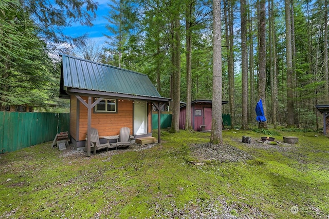 back of property with a fire pit, a yard, and a shed