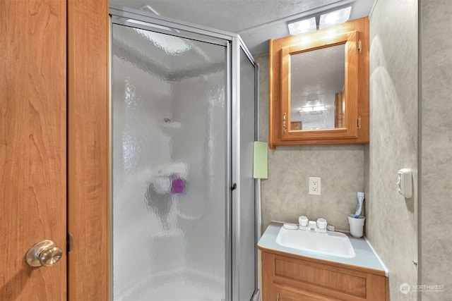 bathroom with large vanity, an enclosed shower, and a textured ceiling