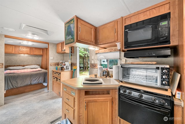 kitchen featuring wall oven, sink, and light tile floors