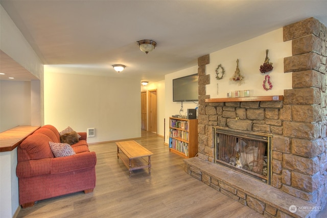 living room featuring a stone fireplace and wood-type flooring