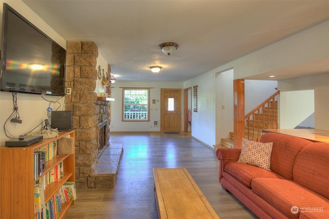 living room featuring a stone fireplace and dark hardwood / wood-style flooring