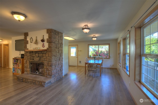 dining space with a stone fireplace and hardwood / wood-style flooring