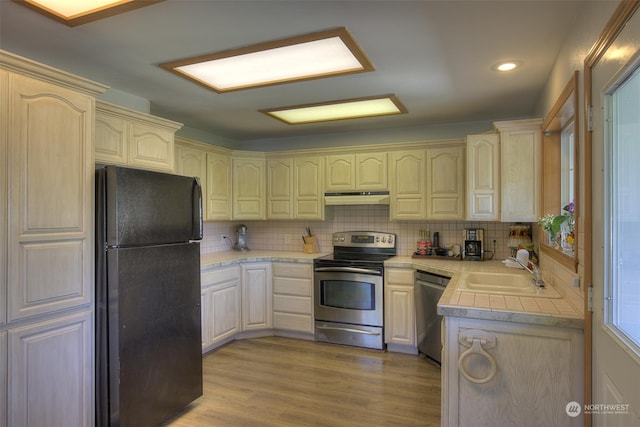 kitchen featuring backsplash, light hardwood / wood-style floors, sink, and stainless steel appliances