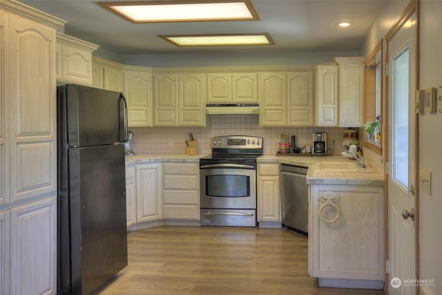 kitchen featuring tile counters, sink, hardwood / wood-style floors, backsplash, and stainless steel appliances