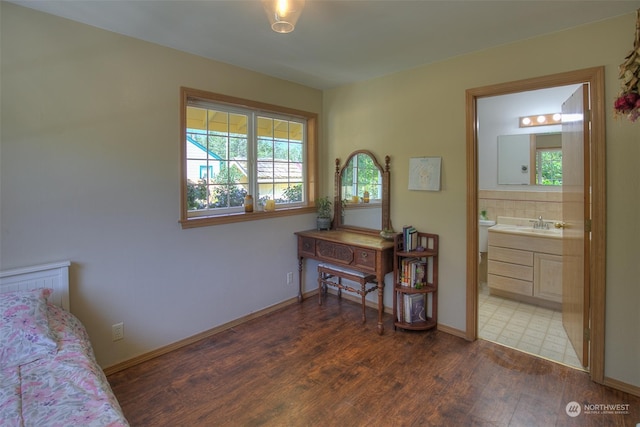 bedroom featuring multiple windows, dark wood-type flooring, sink, and ensuite bathroom