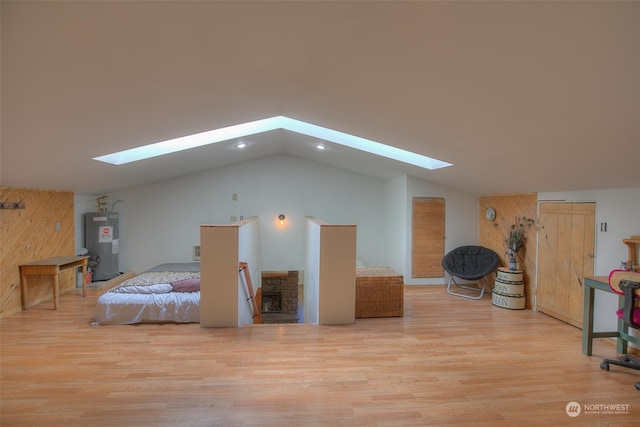 bedroom featuring lofted ceiling with skylight, electric water heater, and light hardwood / wood-style flooring