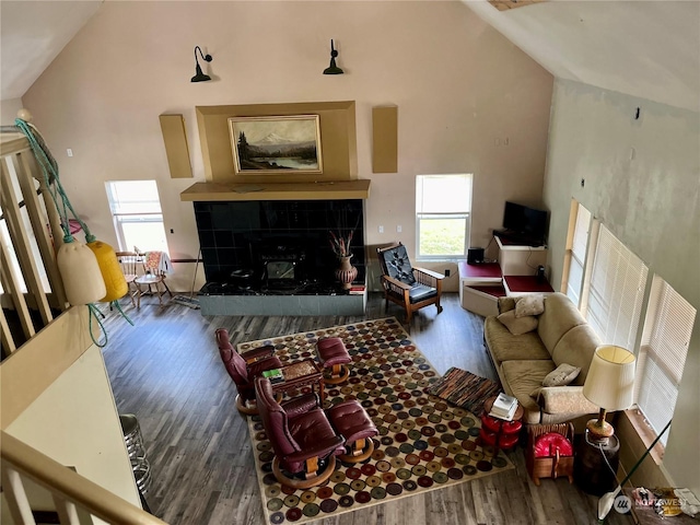 living room featuring a tile fireplace, wood-type flooring, and high vaulted ceiling