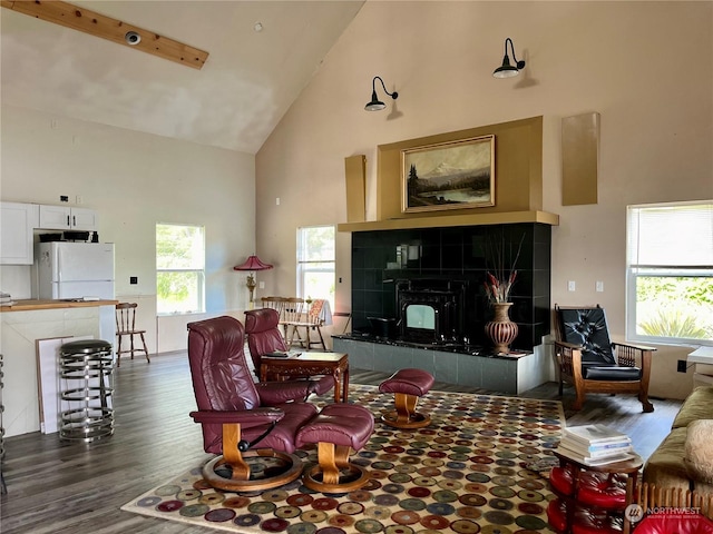 living room with dark hardwood / wood-style flooring, high vaulted ceiling, and a tile fireplace