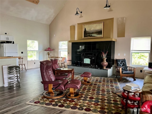 living room featuring a tile fireplace, dark hardwood / wood-style flooring, and high vaulted ceiling