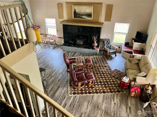 living room with a tiled fireplace, a towering ceiling, and hardwood / wood-style floors