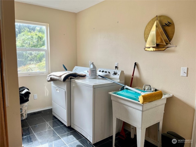 clothes washing area with washing machine and dryer, sink, and dark tile patterned flooring