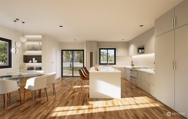 kitchen featuring gray cabinetry, decorative light fixtures, light hardwood / wood-style flooring, a kitchen island, and a breakfast bar area