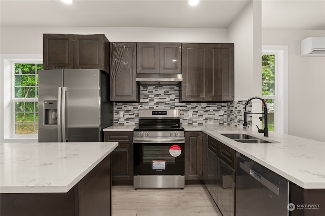 kitchen featuring stainless steel appliances, a wall unit AC, sink, and a wealth of natural light