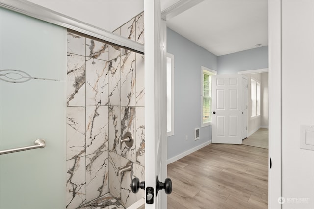 bathroom with hardwood / wood-style floors and tiled shower