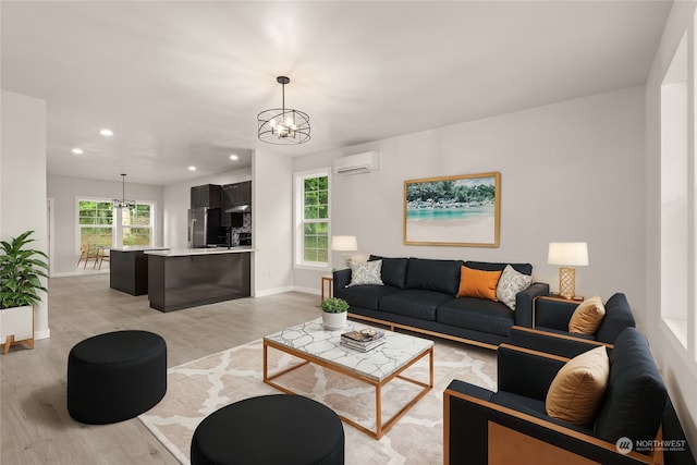 living room with light hardwood / wood-style flooring, a wall mounted air conditioner, an inviting chandelier, and a wealth of natural light