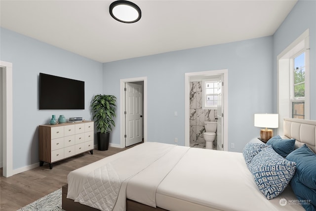 bedroom featuring ensuite bath, hardwood / wood-style floors, and multiple windows