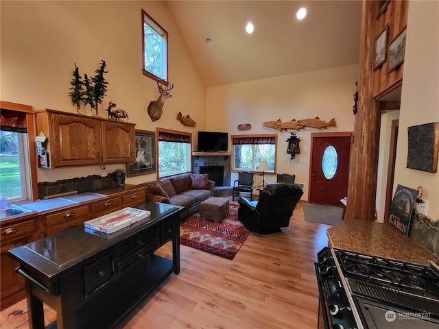 kitchen featuring high vaulted ceiling, light hardwood / wood-style floors, and black range with gas cooktop