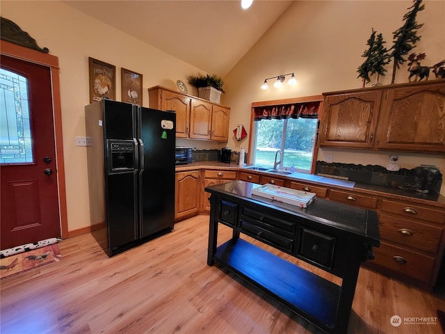 kitchen featuring black fridge, sink, high vaulted ceiling, and light hardwood / wood-style flooring