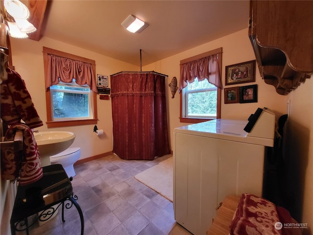 bathroom with sink, toilet, walk in shower, and washer / clothes dryer