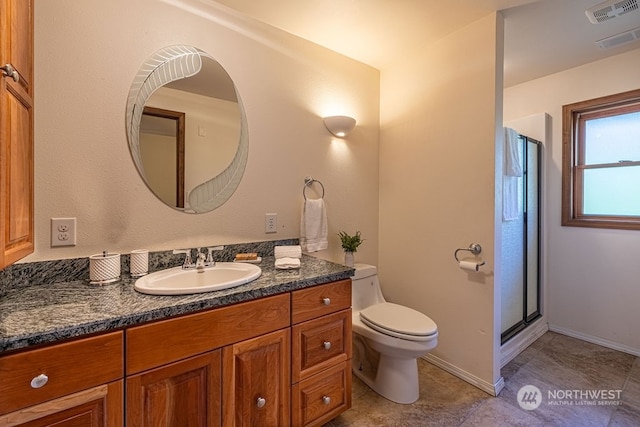 bathroom with tile flooring, toilet, vanity, and a shower with shower door