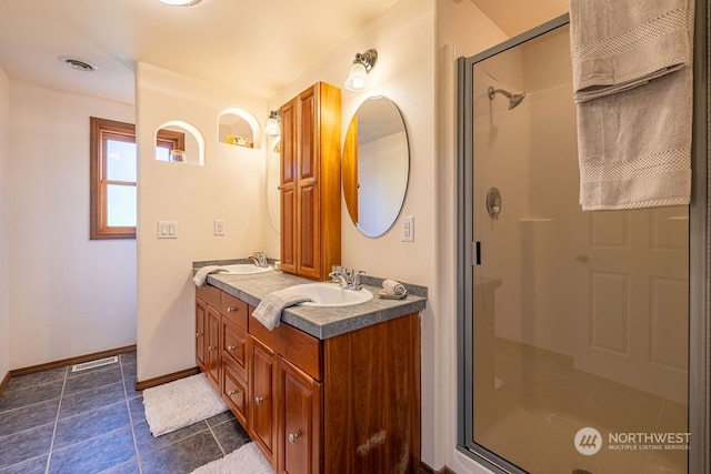 bathroom with double vanity, tile floors, and an enclosed shower