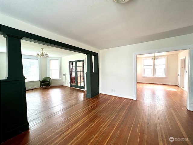 unfurnished room with a notable chandelier, dark hardwood / wood-style floors, and a wealth of natural light