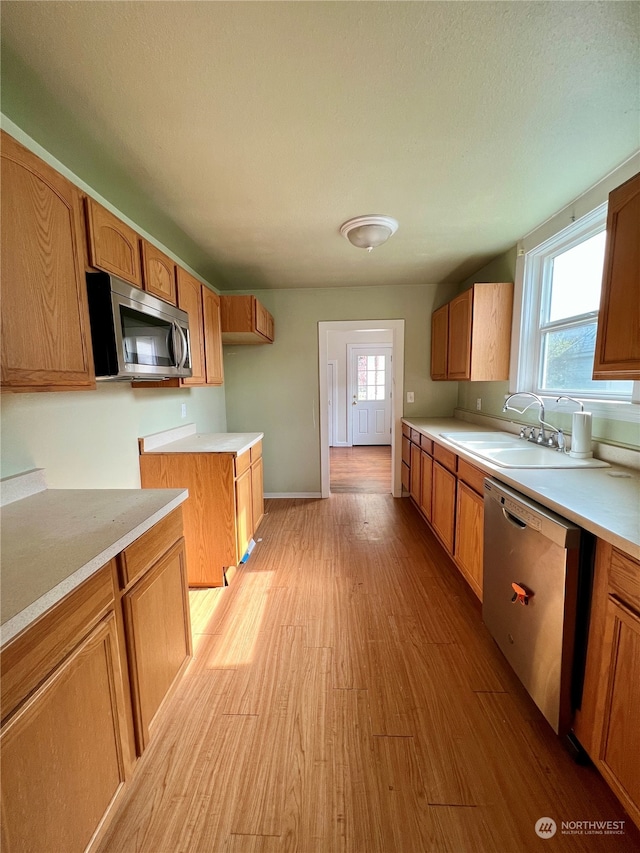 kitchen with plenty of natural light, light hardwood / wood-style floors, appliances with stainless steel finishes, and sink