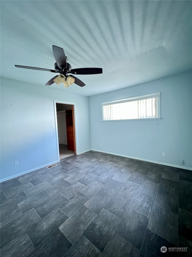tiled empty room featuring ceiling fan