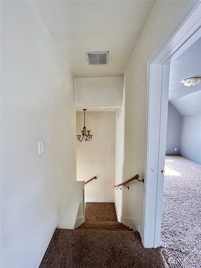 stairs featuring dark carpet, a chandelier, and vaulted ceiling
