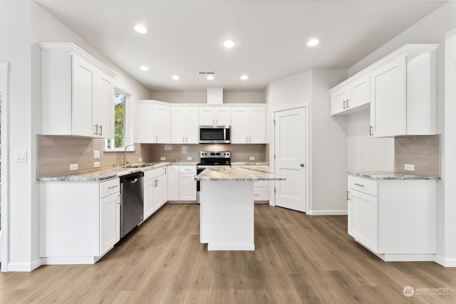 kitchen featuring light wood-type flooring, a center island, appliances with stainless steel finishes, and white cabinetry