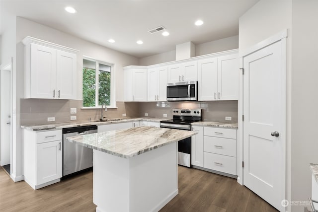 kitchen featuring white cabinetry, appliances with stainless steel finishes, hardwood / wood-style flooring, and a kitchen island