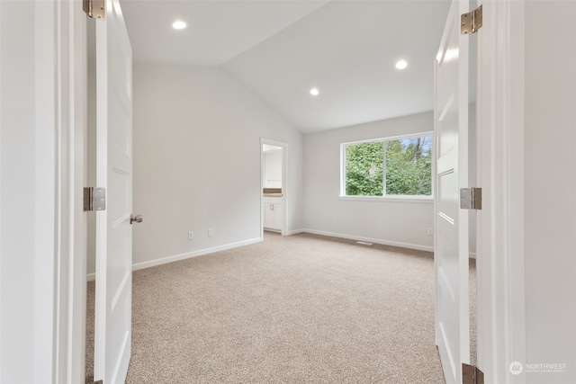 empty room featuring light colored carpet and vaulted ceiling