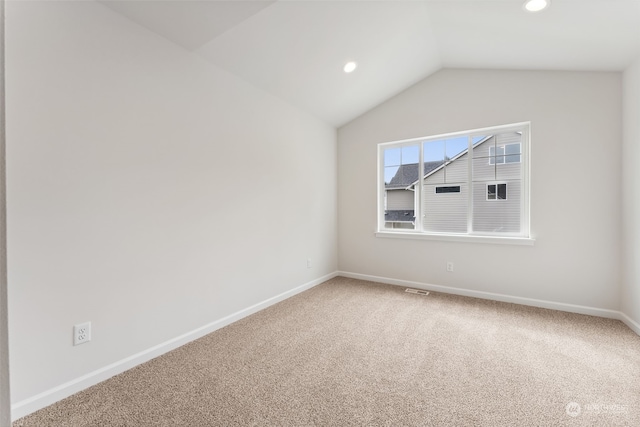 carpeted spare room featuring lofted ceiling