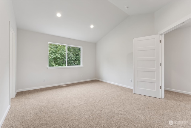 carpeted spare room featuring vaulted ceiling