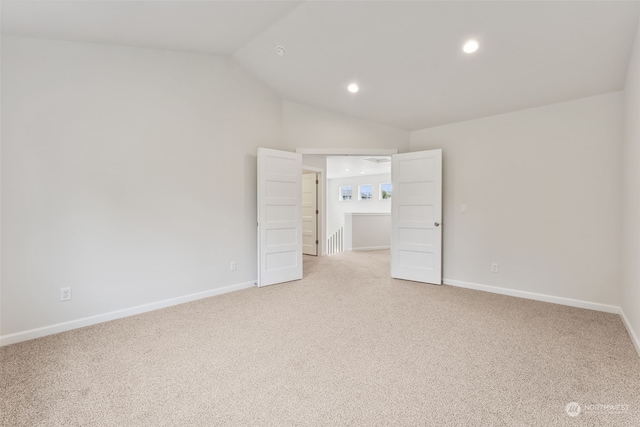 spare room with lofted ceiling and light colored carpet