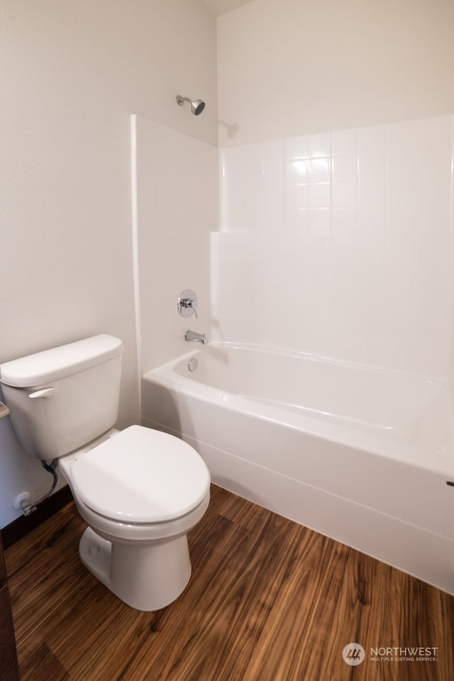 bathroom featuring wood-type flooring, shower / bath combination, and toilet