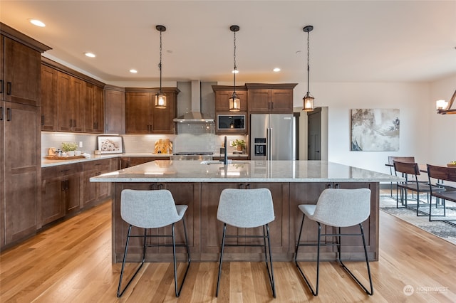 kitchen featuring light hardwood / wood-style floors, wall chimney range hood, black microwave, and high quality fridge