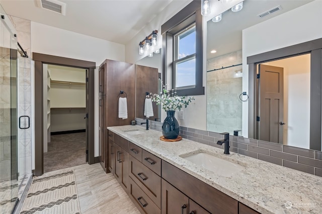 bathroom with backsplash, a shower with shower door, oversized vanity, tile flooring, and dual sinks