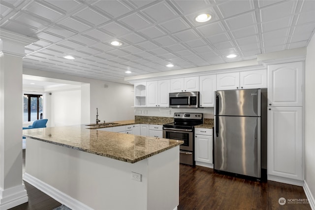 kitchen featuring appliances with stainless steel finishes, dark stone counters, dark wood-type flooring, sink, and white cabinetry