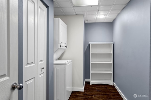 interior space featuring stacked washer / drying machine, a drop ceiling, and dark hardwood / wood-style flooring