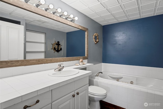 bathroom featuring toilet, large vanity, and tiled tub