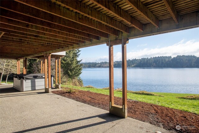 view of patio featuring a water view and a hot tub